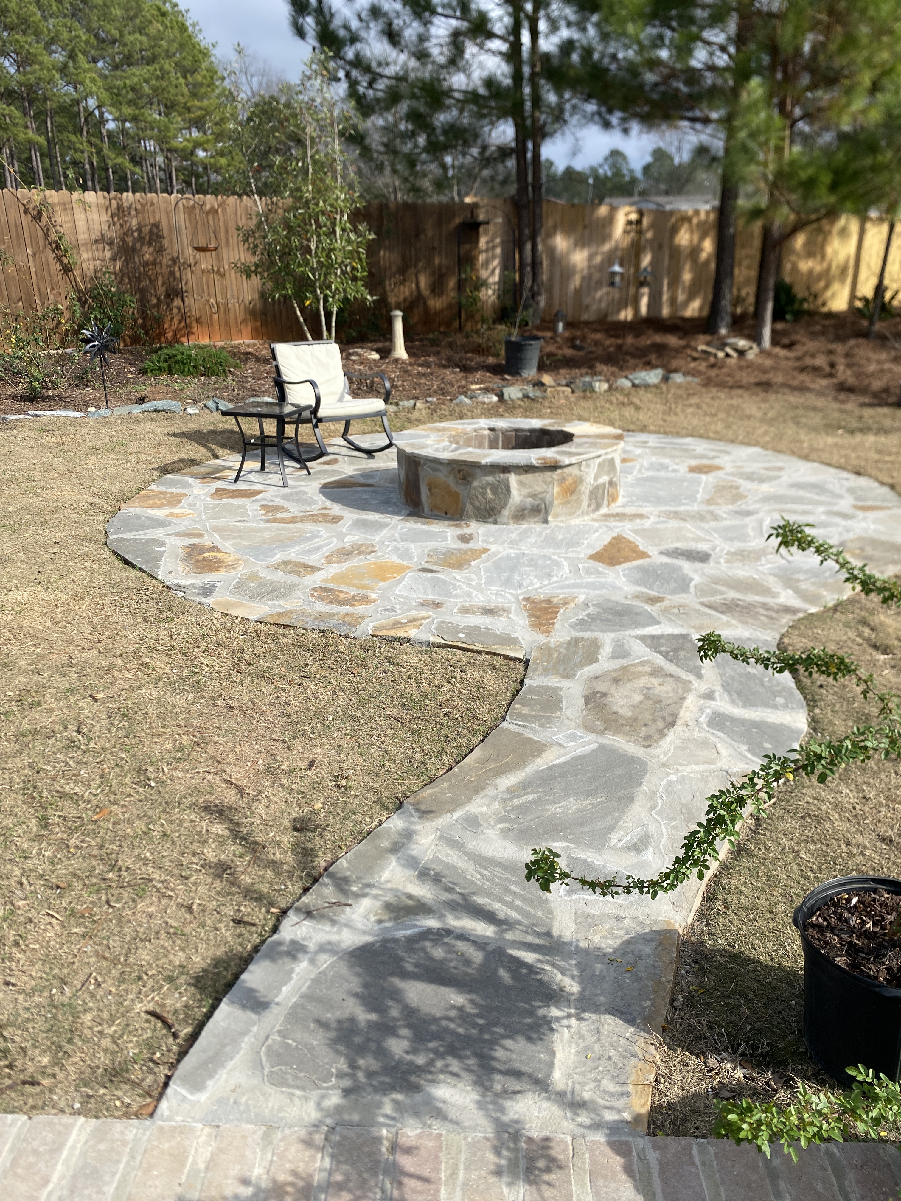 Circular flagstone patio with built-in fire pit in a residential backyard in Opelika, Alabama