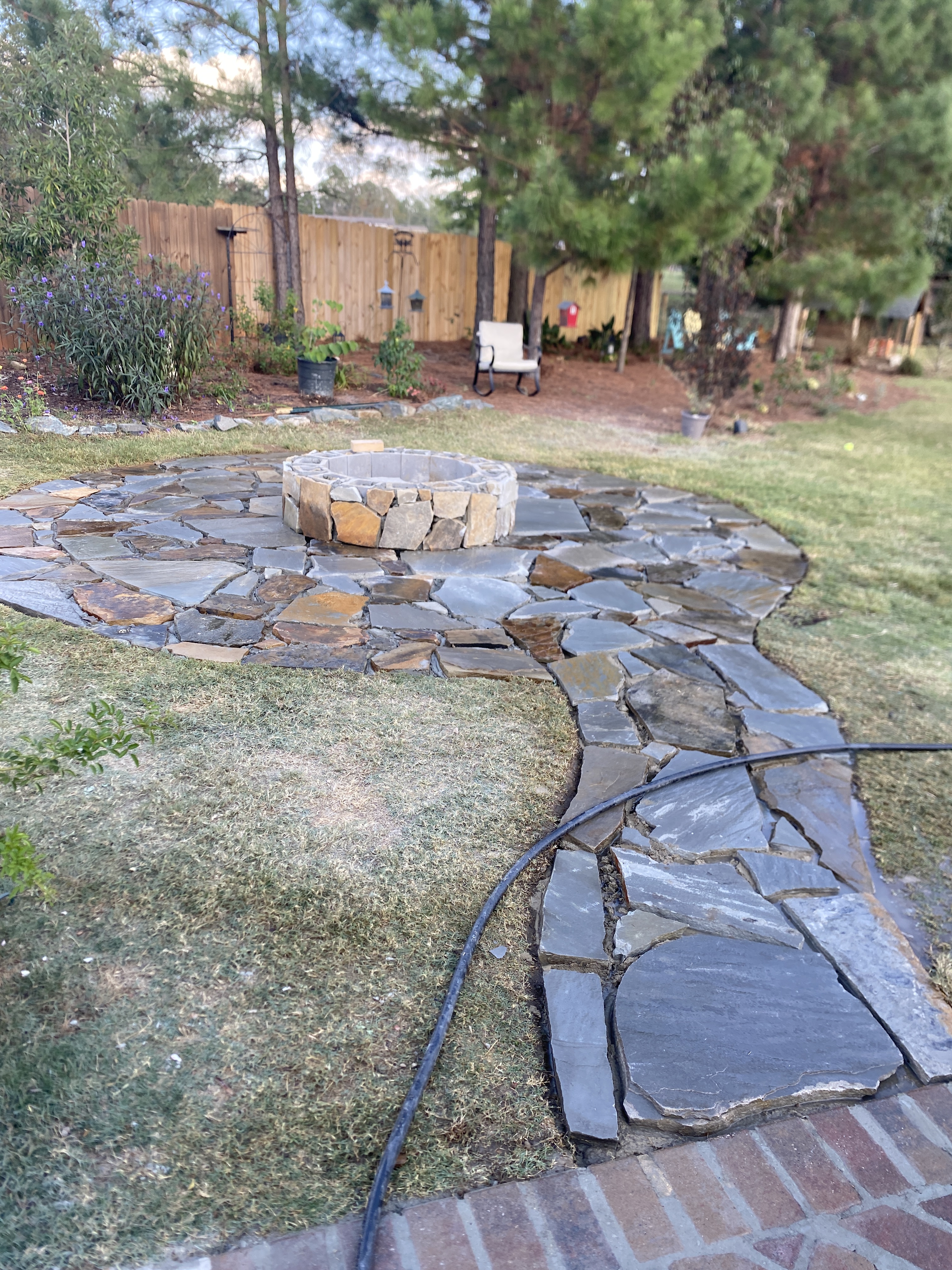 Custom circular flagstone patio with built-in fire pit and flagstone walkway installed in Opelika, Alabama by Recinos Landscape & Outdoor Solutions.
